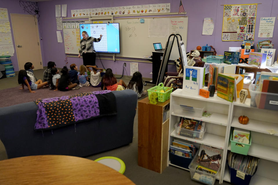 Whittier Elementary School teacher Kaitlyn Dewey instructs her students, Tuesday, Oct. 18, 2022 in Mesa, Ariz. Like many school districts across the country, Mesa has a teacher shortage due in part due to low morale and declining interest in the profession. Five years ago, Mesa allowed Whittier to participate in a program making it easier for the district to fill staffing gaps, grant educators greater agency over their work and make teaching a more attractive career. The model, known as team teaching, allows teachers to combine classes and grades rotating between big group instruction, one-on-one interventions, small study groups or whatever the team agrees is a priority each day. (AP Photo/Matt York)