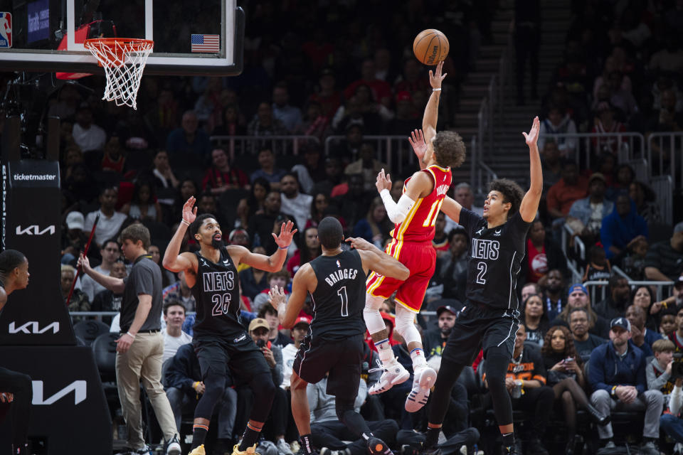 Atlanta Hawks guard Trae Young (11) shoots between Brooklyn Nets forward Mikal Bridges (1) and forward Cameron Johnson during the second half of an NBA basketball game, Sunday, Feb. 26, 2023, in Atlanta. (AP Photo/Hakim Wright Sr.)