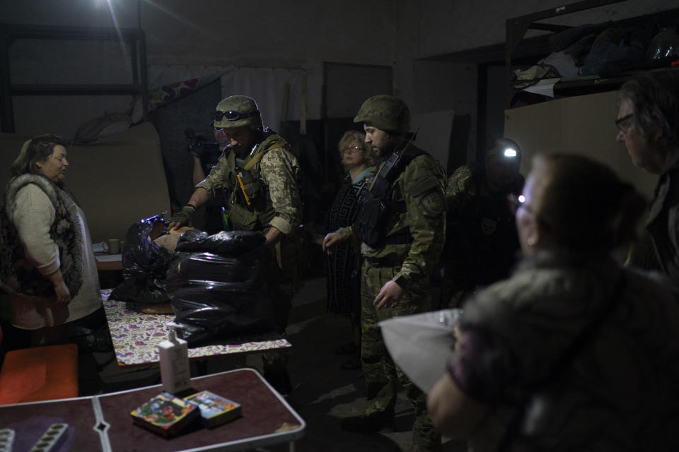 A special task force policemen deliver bags of breads donated to the people who are living inside a basement used as a bomb shelter, during Russian attacks in Severodonetsk, Luhansk region, Ukraine, Friday, May 13, 2022. (AP Photo/Leo Correa)