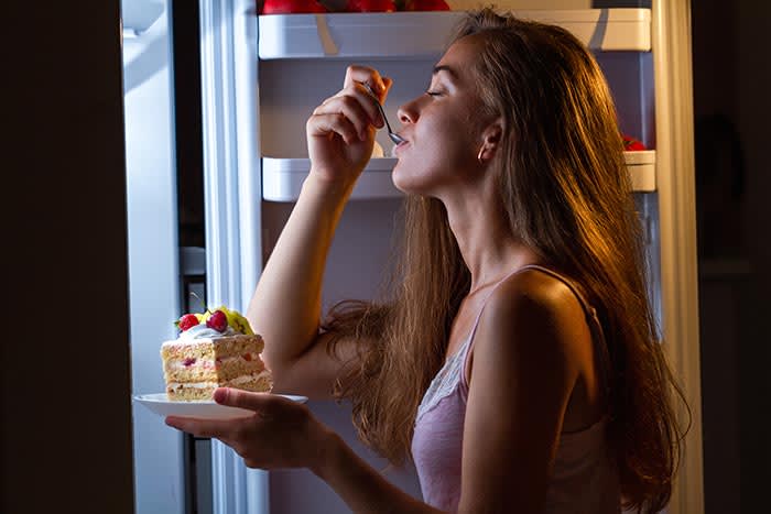 mujer comiendo tarta en la cocina