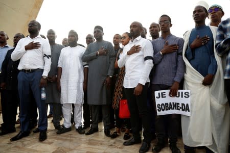 People pay their respects during a remembrance ceremony at the Monument de la Paix in Bamako