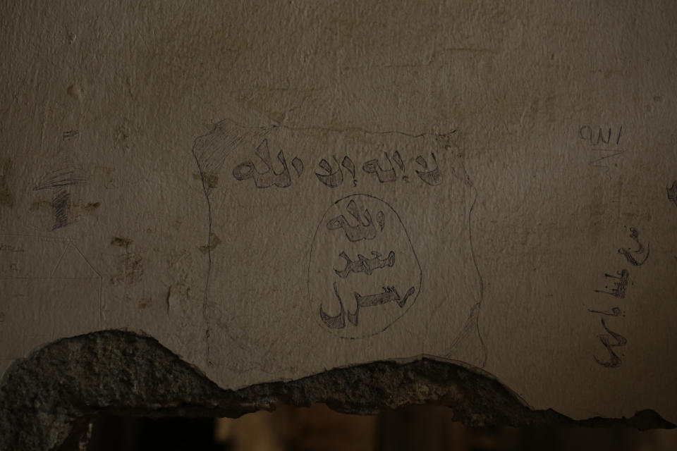 In this Thursday, Sept. 5, 2019, photo, a prisoner's drawing of the Islamic State militant flag remains on the wall of a makeshift IS prison in the basement off the main stadium in Raqqa, Syria. (AP Photo/Maya Alleruzzo)