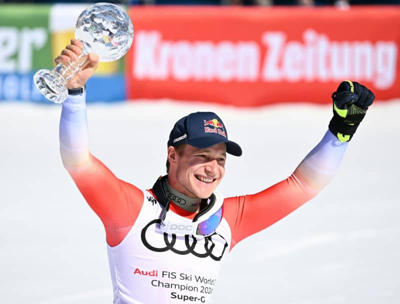 Switzerland's Marco Odermatt celebrates with the overall leader's crystal globe trophy after the men's Super G race during the FIS Ski Alpine World Cup. Barbara Gindl/APA/dpa