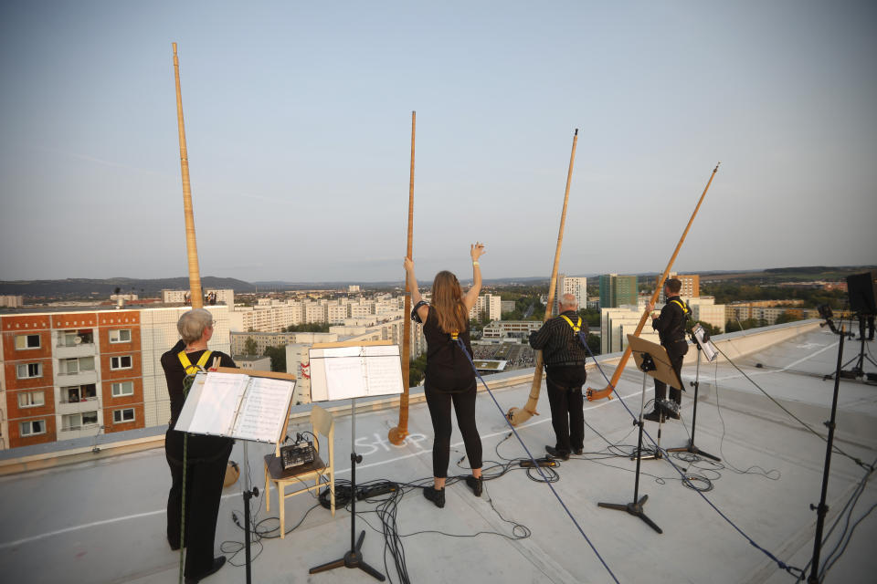 Musicians with alp horns receive applause after performing on the roof of an apartment block for a concert featuring distant harmonies, at a time when cultural events have been disrupted by the coronavirus pandemic, in the Prohlis neighborhood in Dresden, Germany, Saturday, Sept. 12, 2020. About 33 musicians of the Dresden Sinfoniker perform a concert named the 'Himmel ueber Prohils', The Sky above Prohlis, on the roof-tops of communist-era apartment blocs in the Dresden neighborhood Prohlis. (AP Photo/Markus Schreiber)