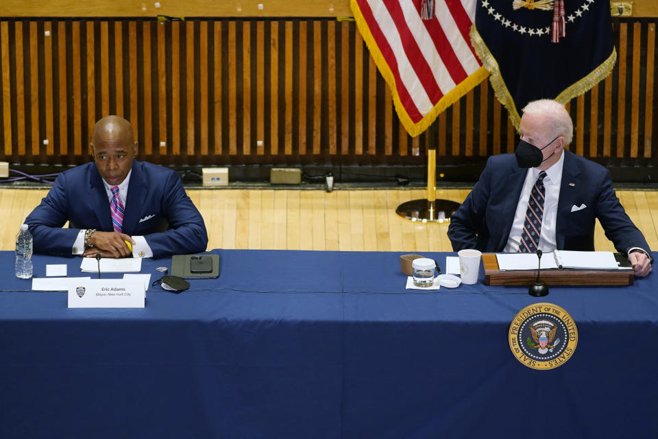 President Biden, in mask, listens to New York City Mayor Eric Adams speak.