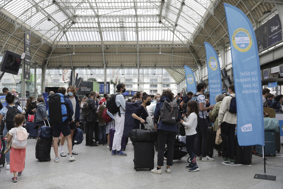 Travelers queue to access trains as railways employees check the COVID-19 health pass that everyone in the country needs to enter cafes, trains and other venues, Monday Aug.9, 2021 at the Gare de Lyon train station in Paris. Starting today, the pass will be required in France to access cafes, restaurants, long-distance travel and, in some cases, hospitals. It was already in place for cultural and recreational venues, including cinemas, concert halls, sports arenas and theme parks with a capacity for more than 50 people. (AP Photo/Adrienne Surprenant)