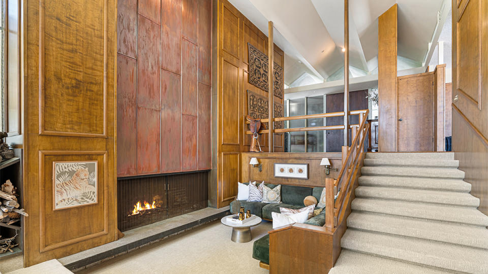 The sunken living room includes a snug seating area with built-in sofas alongside a massive copper fireplace.