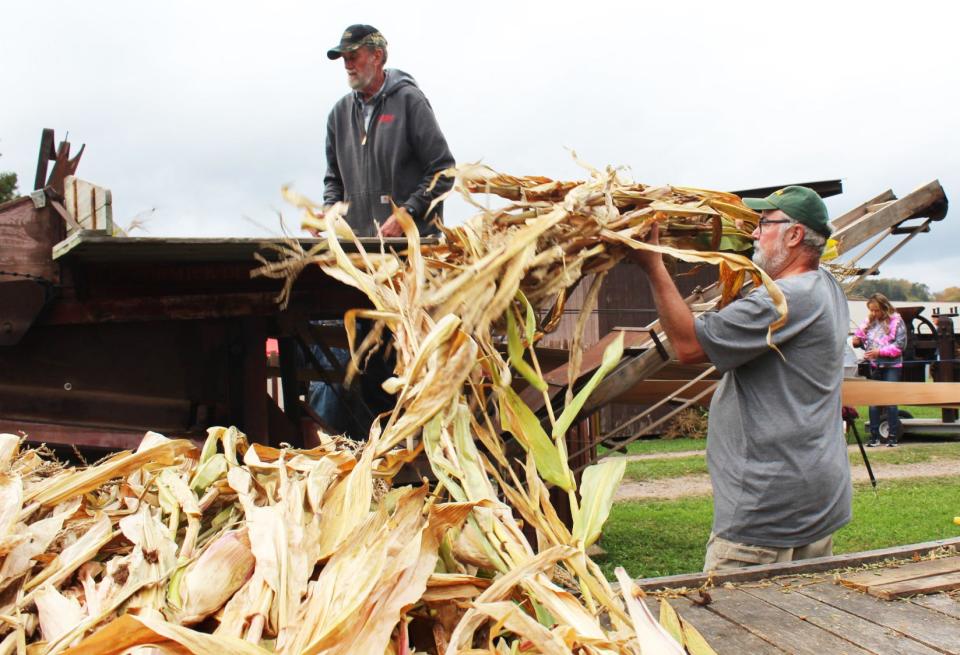 Don Betler throws corn stalks up to Reuben Tice as part of a husker shredder demonstration at Springs Folk Fest on Friday.