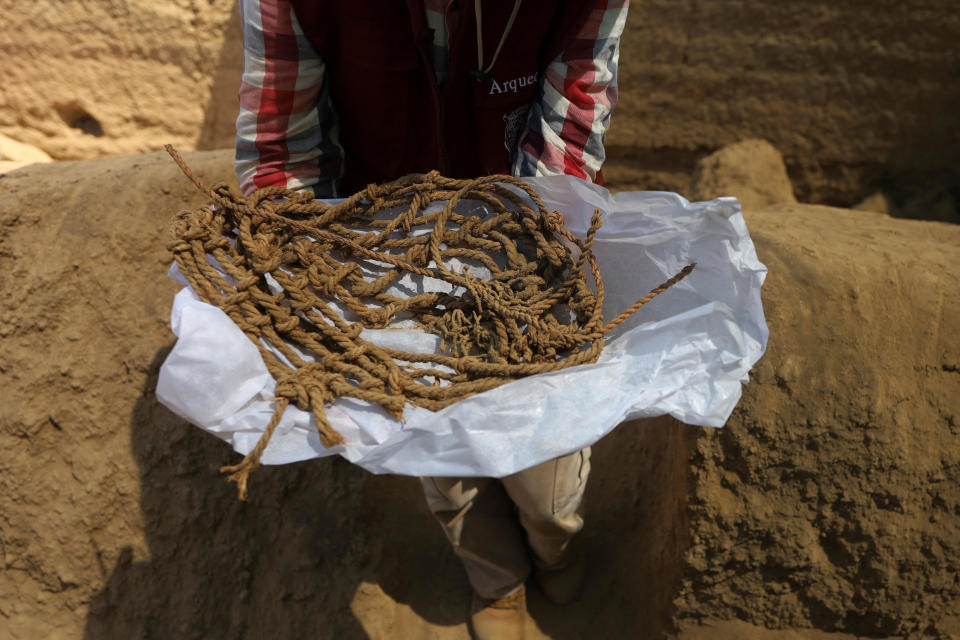 A worker holds parts of the funerary bundle of a mummy found by Peruvian archaeologists in the ruins of Cajarmarquilla, in the outskirts of Lima, Peru. April 24, 2023. / Credit: SEBASTIAN CASTANEDA / REUTERS