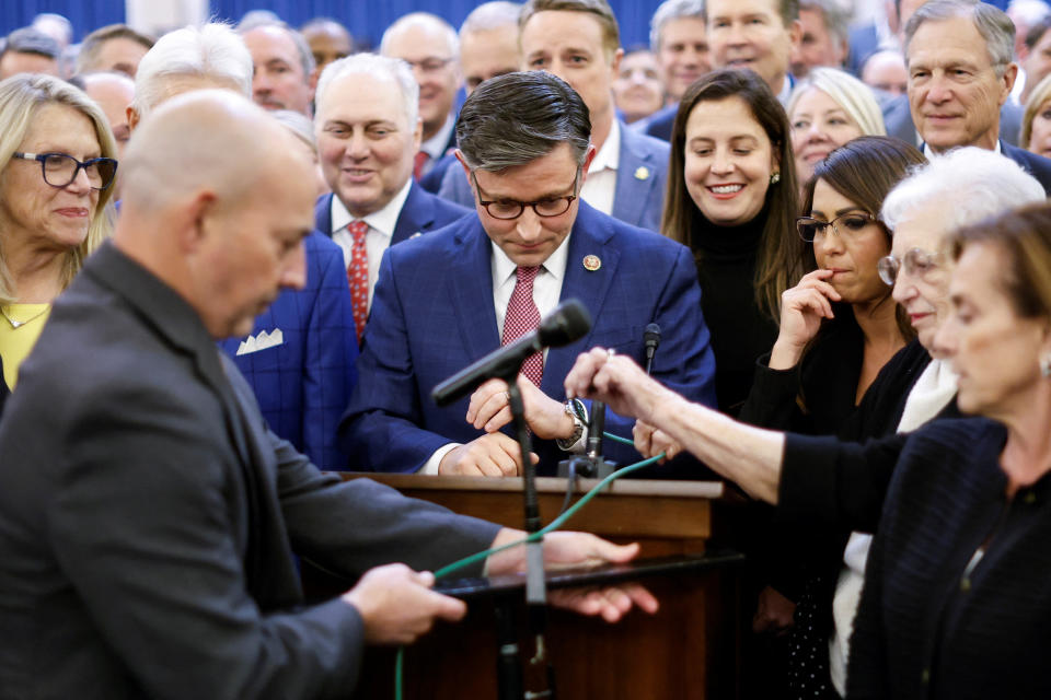 Representative Mike Johnson stands at a podium, surrounded by other House members.