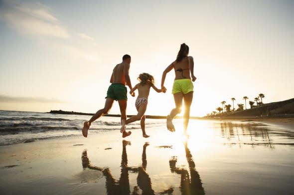 Family running on beach at sunset