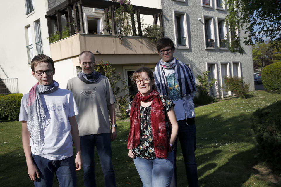 In this photo taken Thursday, April 16, 2020, Jerome, second left, Nadege and their children Thomas, 17, right and Pierre, 14, both with intellectual disabilities pose outside their apartment in Montigny-le-Bretonneux, near Paris. Coronavirus lockdown is proving an ordeal for kids with disabilities and their families who are having to care for them at home because special schools have been shut down to curb infections. The family requested to be identified by their first name out of concern for privacy. (AP Photo/Christophe Ena)