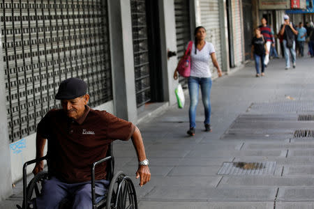 A man in a wheelchair passes in front of a closed store at a commercial area in Caracas, Venezuela August 21, 2018. REUTERS/Carlos Garcia Rawlins