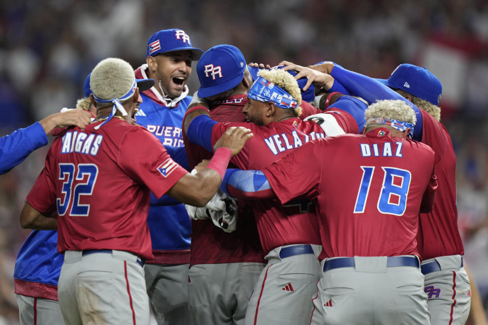 Puerto Rico pitcher Edwin Diaz, center, is mobbed by teammates after Puerto Rico beat the Dominican Republic 5-2 during a World Baseball Classic game, Wednesday, March 15, 2023, in Miami. Diaz appeared to injure himself during the postgame celebration. (AP Photo/Wilfredo Lee)