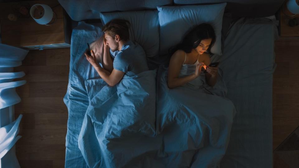 Silently scrolling on social media at night while laying in bed could hurt your relationship, experts say, offering some tips to unplug from the screens and connect with each other. Gorodenkoff – stock.adobe.com