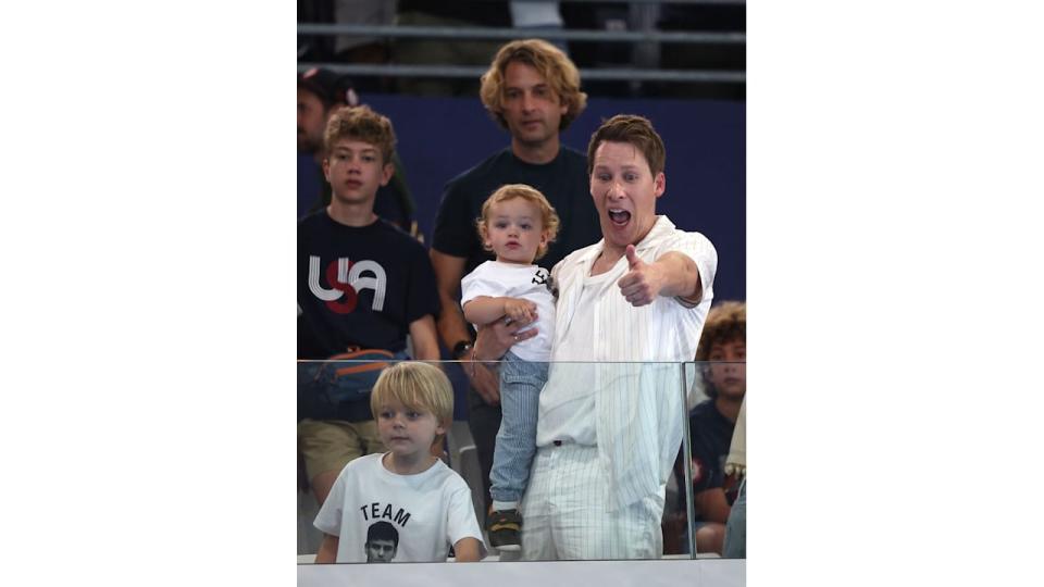 Dustin Lance Black with a thumbs up holding his son Phoenix