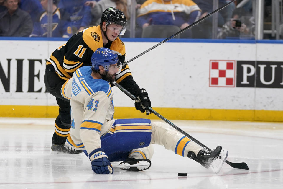 St. Louis Blues' Robert Bortuzzo (41) and Boston Bruins' Trent Frederic (11) chase after a loose puck during the third period of an NHL hockey game Tuesday, April 19, 2022, in St. Louis. (AP Photo/Jeff Roberson)