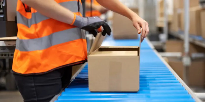 A woman closing a box on a conveyer belt