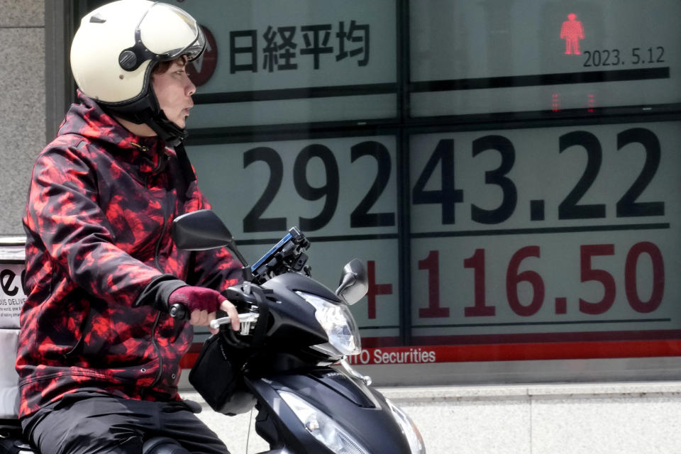 A person rides past an electronic stock board showing Japan's Nikkei 225 index at a securities firm Friday, May 12, 2023, in Tokyo. Asian shares were mostly lower Friday on looming worries over U.S. banks and lagging demand from China, the region's major driver of growth. (AP Photo/Eugene Hoshiko)