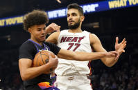 Phoenix Suns' Cameron Johnson, left, pulls down a rebound against Miami Heat's Omer Yurtseven (77) during the first half of an NBA basketball game Saturday, Jan. 8, 2022, in Phoenix. (AP Photo/Darryl Webb)