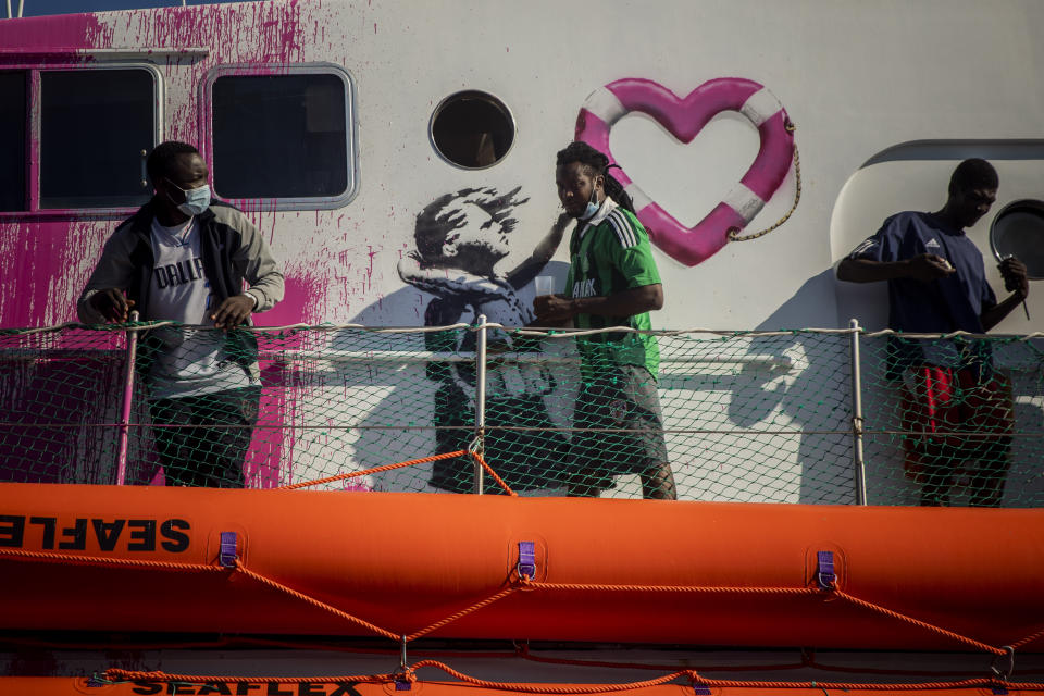 A man walks past a painting by British artist Banksy on the deck of the Louise Michele rescue vessel, after performing 2 rescue operations on the high seas in the past days, 70 miles south west Malta, Central Mediterranean sea, Saturday, Aug. 29, 2020. A rescue ship painted and sponsored by British artist Banksy saved another 130 migrants stranded on a rubber boat in the Southern Mediterranean Sea. (AP Photo/Santi Palacios)