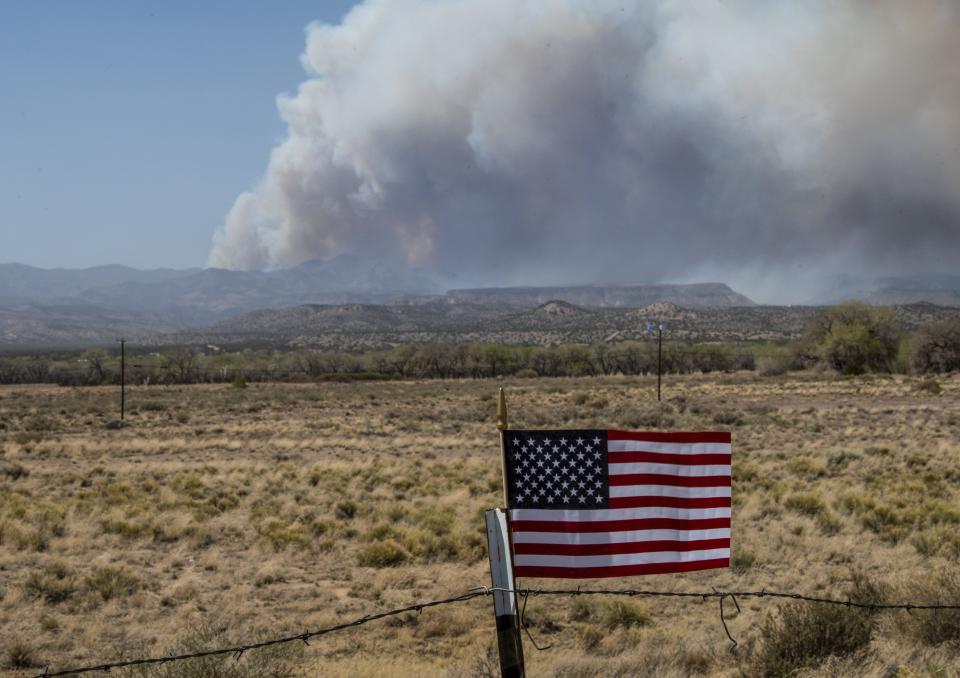 An American Flag on a fence blows in the wind as a wildfire burns April 29 in Cochiti, N.M..
