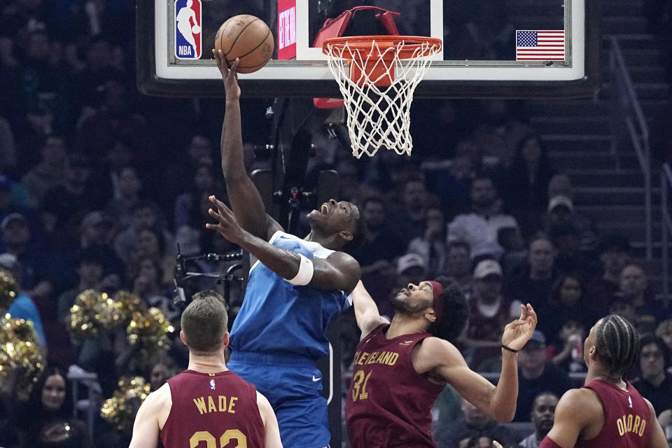 Minnesota Timberwolves guard Anthony Edwards (5) shoots from between Cleveland Cavaliers forward Dean Wade, left, center Jarrett Allen (31) and forward Isaac Okoro during the first half of an NBA basketball game, Friday, March 8, 2024, in Cleveland. (AP Photo/Sue Ogrocki)
