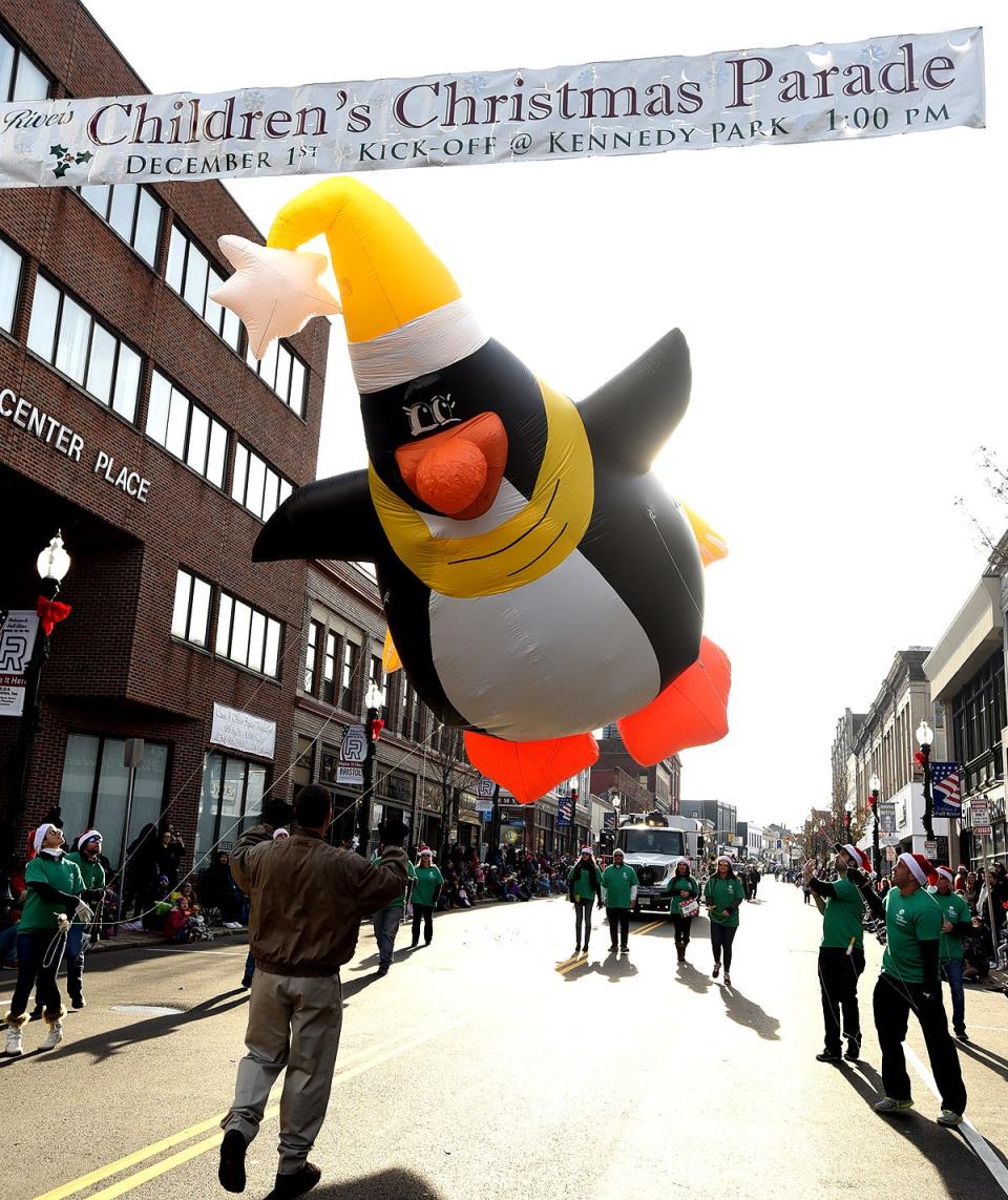 Members of Liberty Utilities team wrangle "Peter Penguin" beneath the banner heralding the Fall River Children's Holiday Parade, Saturday, December 1, 2018, in Fall River, Massachusetts.