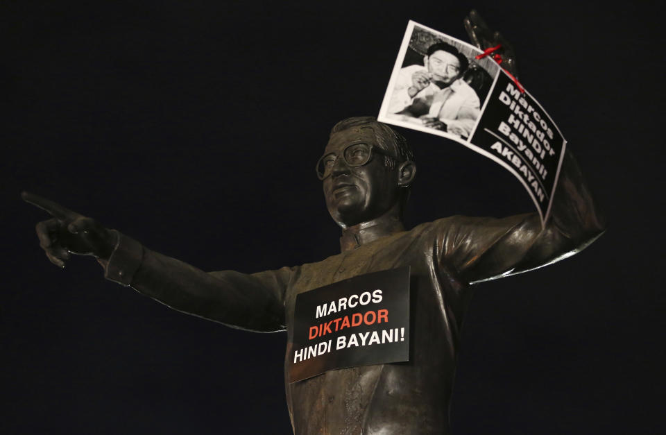 A picture of the late former Philippine dictator Ferdinand Marcos with a slogan that reads "Marcos Dictator, Not a Hero!" is placed on the statue of the late senator Benigno "Ninoy" Aquino Jr., father of former President Benigno Aquino III as people gather at the People's Power Monument in Quezon city, Philippines Friday, Nov. 18, 2016 to protest against the burial of Marcos at the heroes cemetery. Filipino voters overwhelmingly elected Ferdinand "Bongbong" Marcos Jr., as president during the May 2022 elections, completing a stunning return to power for the family of the late President Ferdinand Marcos, Sr., who ruled the country for more than two decades until being ousted in 1986 in the nonviolent "People Power" revolution. (AP Photo/Aaron Favila, File)