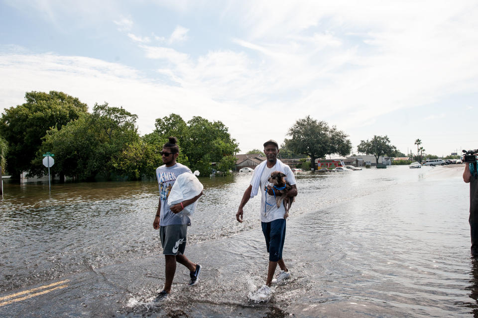 Jared Clark, 19, and Charles Clark, 50, &nbsp;from Port Arthur, walk out of the flood zone with their dog, Tia, after being rescued from their flooded home.