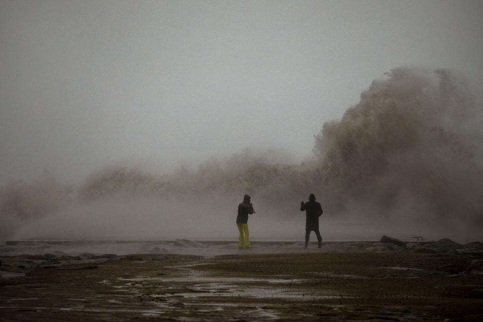 A couple take photographs of the Mediterranean sea as the waves hit the breakwater during a storm in Barcelona, Spain, Tuesday, Jan. 21, 2020. A winter storm lashed much of Spain for a third day Tuesday, leaving 200,000 people without electricity, schools closed and roads blocked by snow as it killed four people. Massive waves and gale-force winds smashed into seafront towns, damaging many shops and restaurants. (AP Photo/Emilio Morenatti)