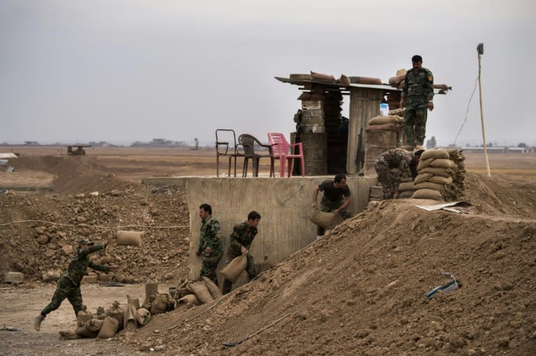 Peshmerga fighters fortify their position along a sand berm north of Shaqouli