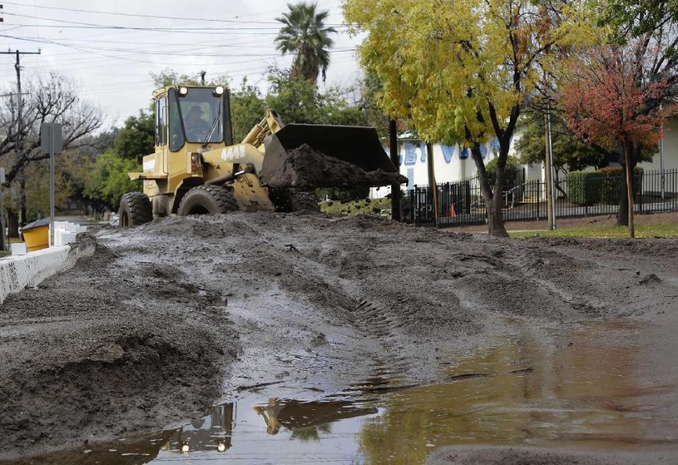 Heavy machinery is used to remove mud and debris that flowed down slopes previously denuded by wildfires in Duarte, Calif., Friday, Dec. 16, 2016. A late fall storm has drenched California, causing some mud flows, roadway flooding and traffic snarls as it takes parting shots at the south end of the state. (AP Photo/Nick Ut)