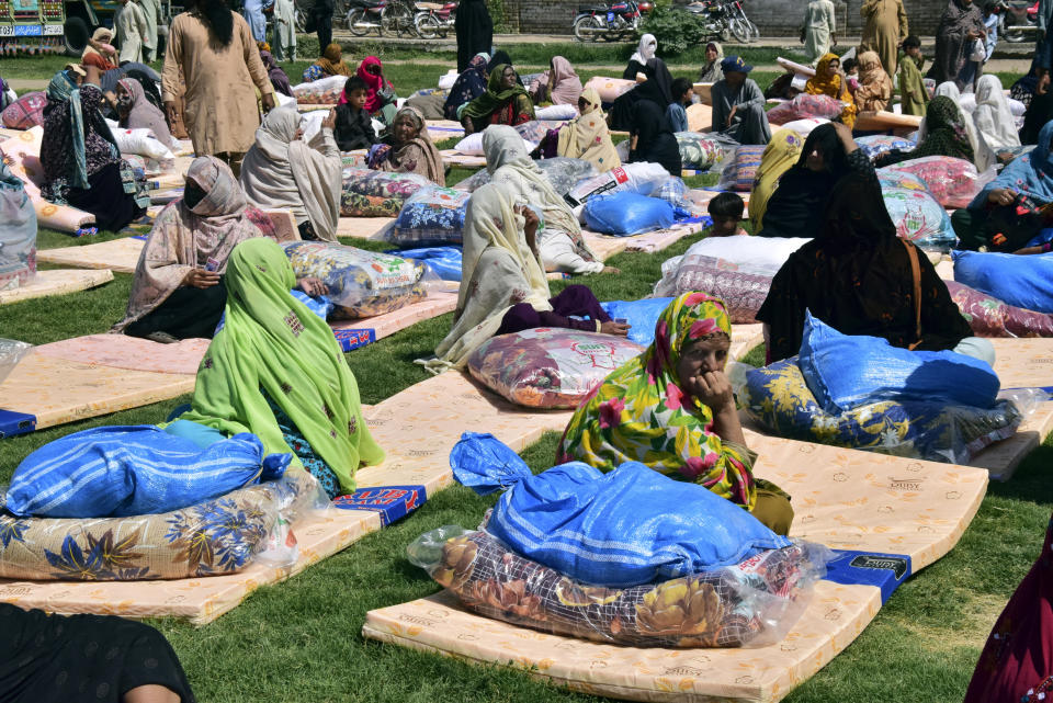 Victims of heavy flooding from monsoon rains receive relief aid provided by the Allah-o-Akbar Tehreek political party, in Quetta, Pakistan, Sunday, Sept. 11, 2022. Since June, heavy rains and flooding have added a new level of grief to cash-strapped Pakistan and highlighted the disproportionate effect of climate change on impoverished populations. (AP Photo/Arshad Butt)