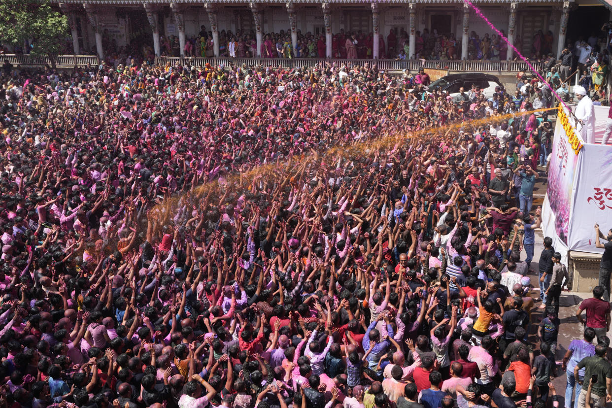 Devotees cheer as colored powder and water is sprayed on them during celebrations marking Holi at the Kalupur Swaminarayan temple in Ahmedabad, India, Wednesday, March 8, 2023. Millions of Indians on Wednesday celebrated the ''Holi" festival, dancing to the beat of drums and smearing each other with green, yellow and red colors and exchanging sweets in homes, parks and streets. Free from mask and other COVID-19 restrictions after two years, they also drenched each other with colored water.(AP Photo/Ajit Solanki)