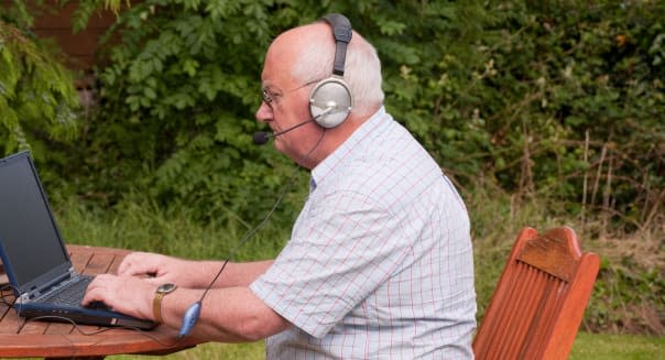 senior male outside using laptop to make voip call