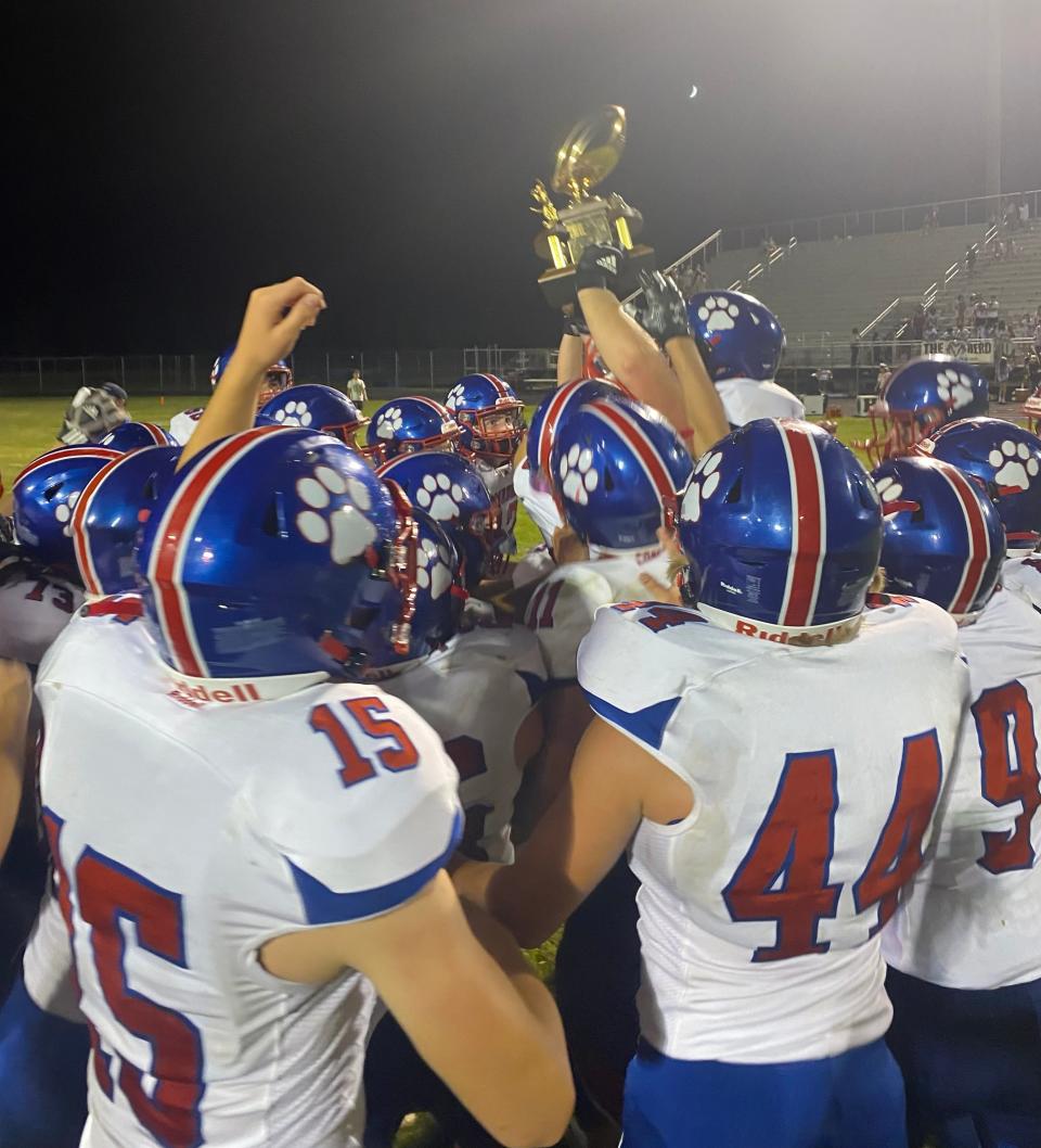 The Mason football team celebrates with the Cedar Street Bowl trophy following its 35-12 win over Holt on Thursday, Sept. 1, 2022.
