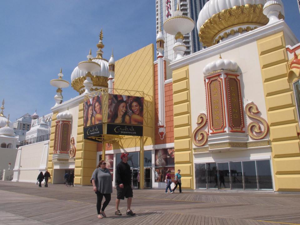 Pedestrians on the Atlantic City N.J. boardwalk look up at the newly renovated facade of the Trump Taj Mahal Casino Resort on Monday, April 8, 2013. Atlantic City tourism officials unveiled a new $20 million advertsing campaign on Tuesday, April 9, 2013, designed to bring more visitors to the seaside gambling resort. (AP Photo/Wayne Parry)