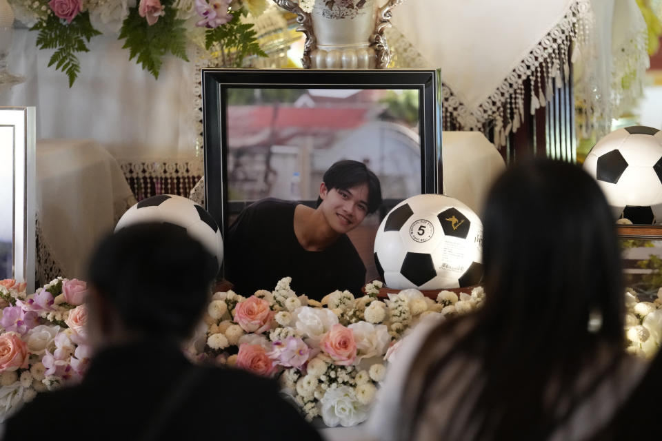 Family members sit in front of portrait Duangphet Phromthep during his funeral at Wat Phra That Doi Wao temple in Chiang Rai province Thailand, Sunday, March 5, 2023. The cremated ashes of Duangphet, one of the 12 boys rescued from a flooded cave in 2018, arrived in the far northern Thai province of Chiang Rai on Saturday where final Buddhist rites for his funeral will be held over the next few days following his death in the U.K. (AP Photo/Sakchai Lalit)