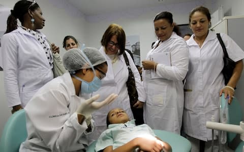 Cuban doctors observe a dental procedure during a a training session at a health clinic in Brasilia - Credit:  Eraldo Peres/AP