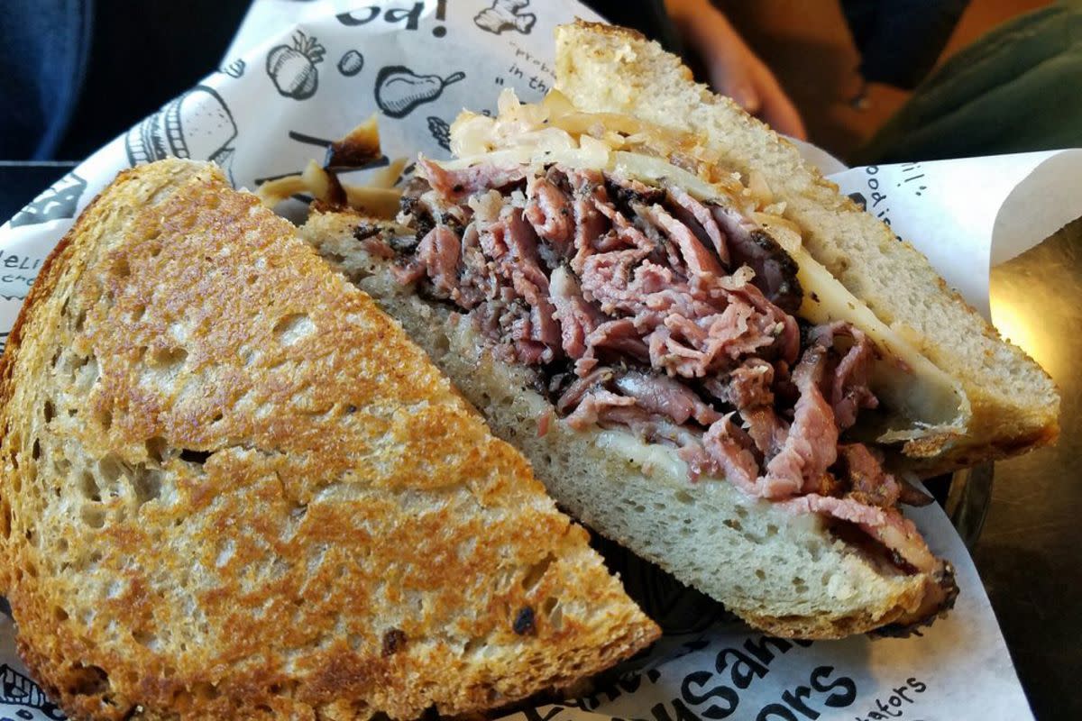 Closeup of Reuben Sandwich on logo serving paper, Zingerman's, Ann Arbor, Michigan, blurred background