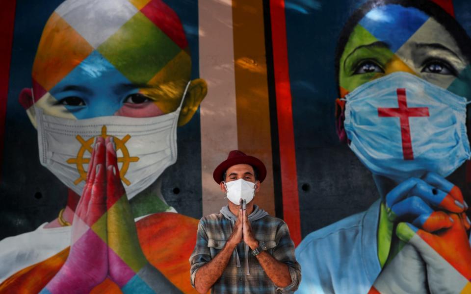 Brazilian graffiti artist Eduardo Kobra poses for a picture in front of his mural in Sao Paulo - Reuters