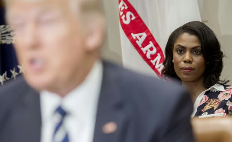 President Donald Trump (L) has now branded Omarosa Manigault Newman (R, in focus) a "dog" as their spat over her dismissal and recording of conversations in the White House escalated