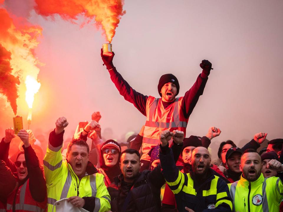 A protester holds a flare as public and private workers demonstrate and shout slogans during a mass strike against pension reforms on December 05, 2019 in Marseille, France.