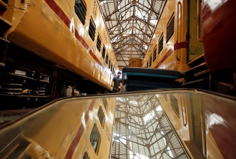 A worker wearing a protective mask walks in between passenger trains in which beds are being installed to set up isolation facilities amid concerns about the spread of coronavirus disease (COVID-19), in Chennai