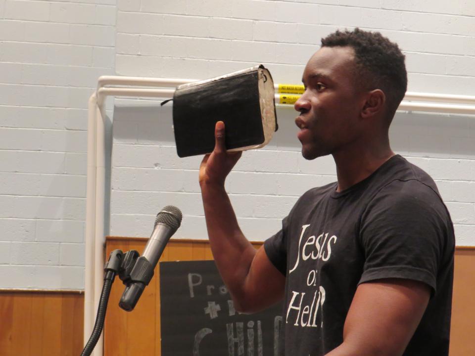 A critic of books available in the Roxbury High School library holds a Bible while making a point.