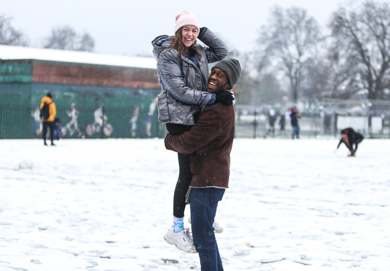 A man carries his girlfriend while playing in the snow on Clapham Common, London, as parts of the UK and Ireland woke up to snow and ice on Sunday morning.