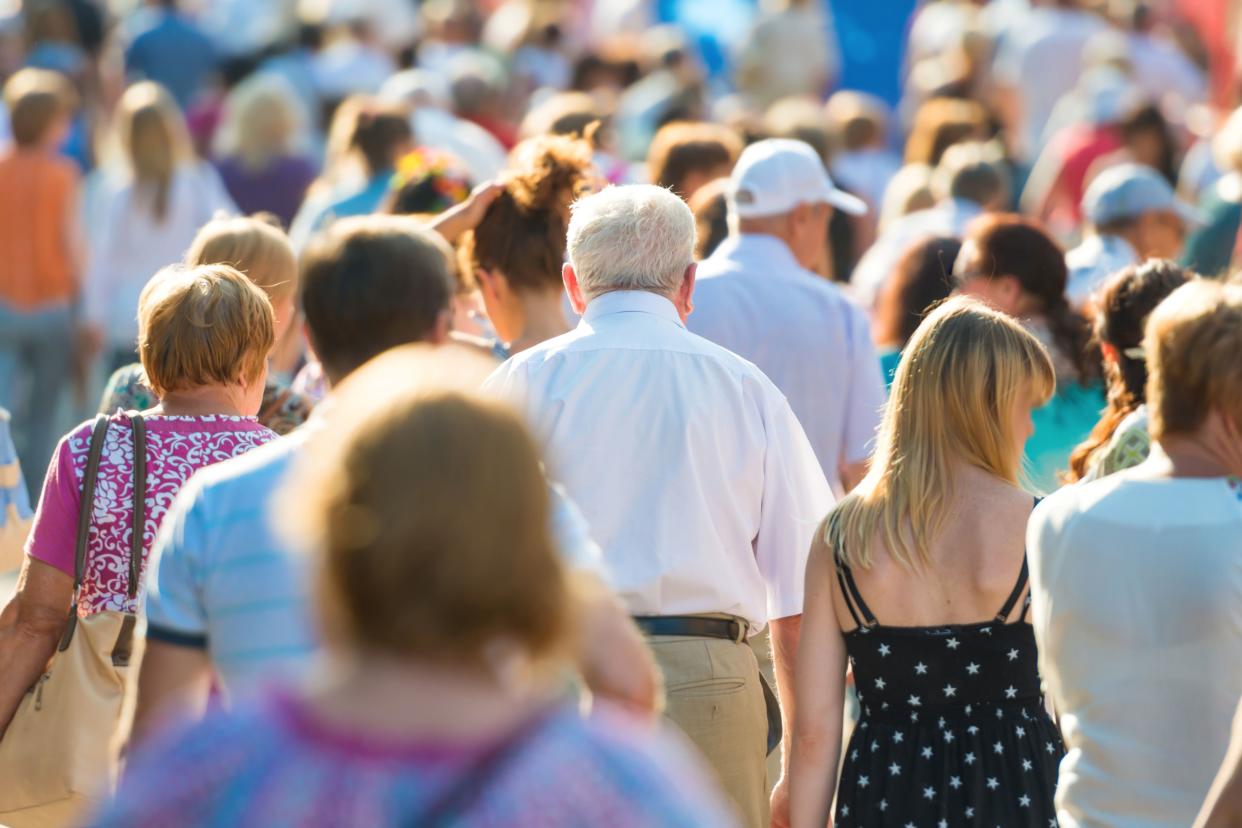 Crowd of people with old man in center walking on the busy city street