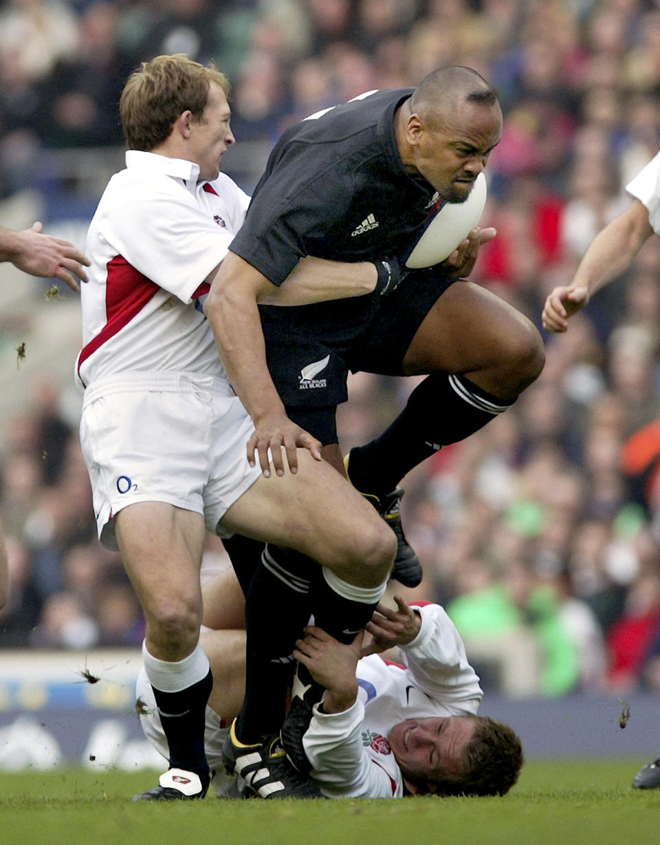 FILE - In this Nov. 10, 2002, file photo, New Zealand All Black winger Jonah Lomu, right, charges over England players Jonny Wilkinson, bottom, and Matt Dawson during their international rugby match at Twickenham in London, England. One trampling run launched Jonah Lomu to global stardom and ensured his name will be indelibly linked to a Rugby World Cup semifinal between New Zealand and England. The All Blacks winger’s rampaging runs during that era-defining World Cup in South Africa in 1995 were highlighted by his four-try haul against England in the semifinals. New Zealand and England meet again in the semifinals this Saturday, Oct. 26, 2019, at Yokohama. (Kenny Rodger/New Zealand Herald via AP, File)