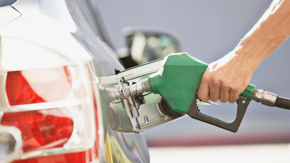 Male hand grips petrol pump as he fills up car.